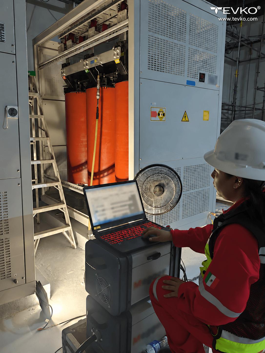 A TEVKO specialist beside an open dry-type transformer and a measurement laptop.