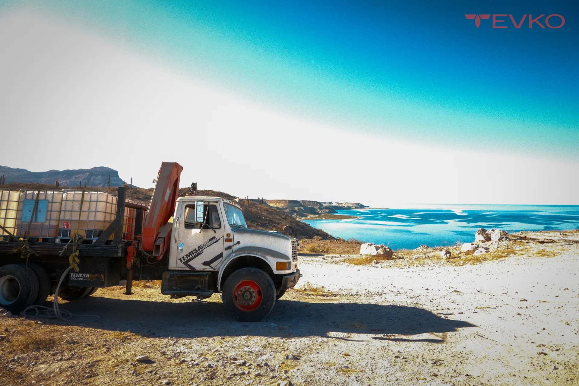 Camión grúa con contenedores IBC en una instalación junto al mar