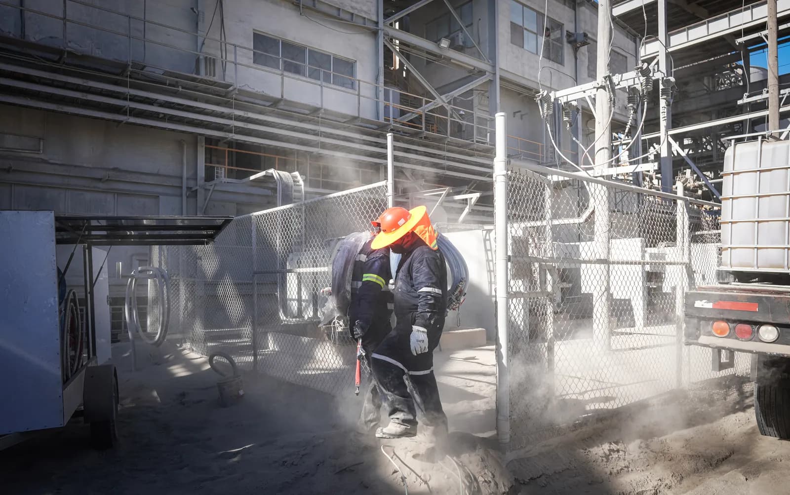 Técnico con hidrolavadora limpiando el equipo de una subestación entre nubes de vapor de agua