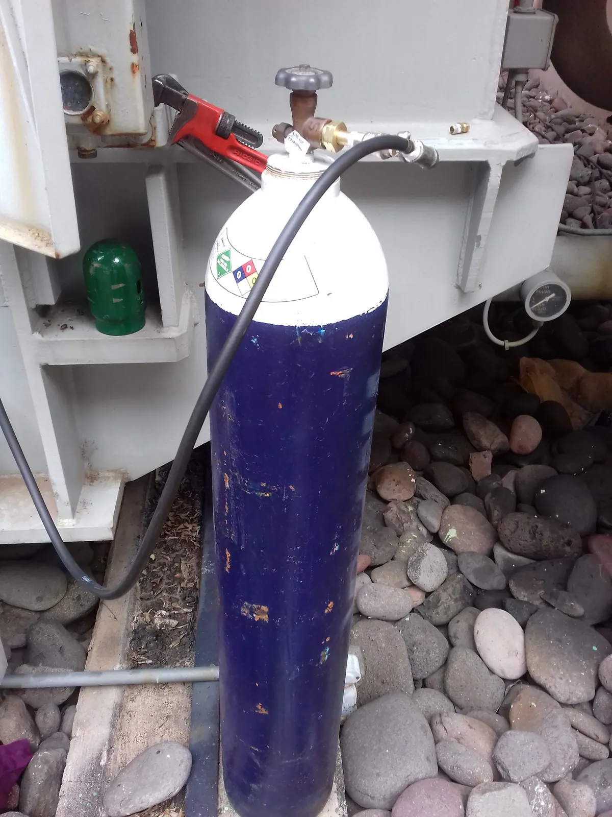 Cilindro de nitrógeno con su regulador conectado por manguera a la válvula de un transformador