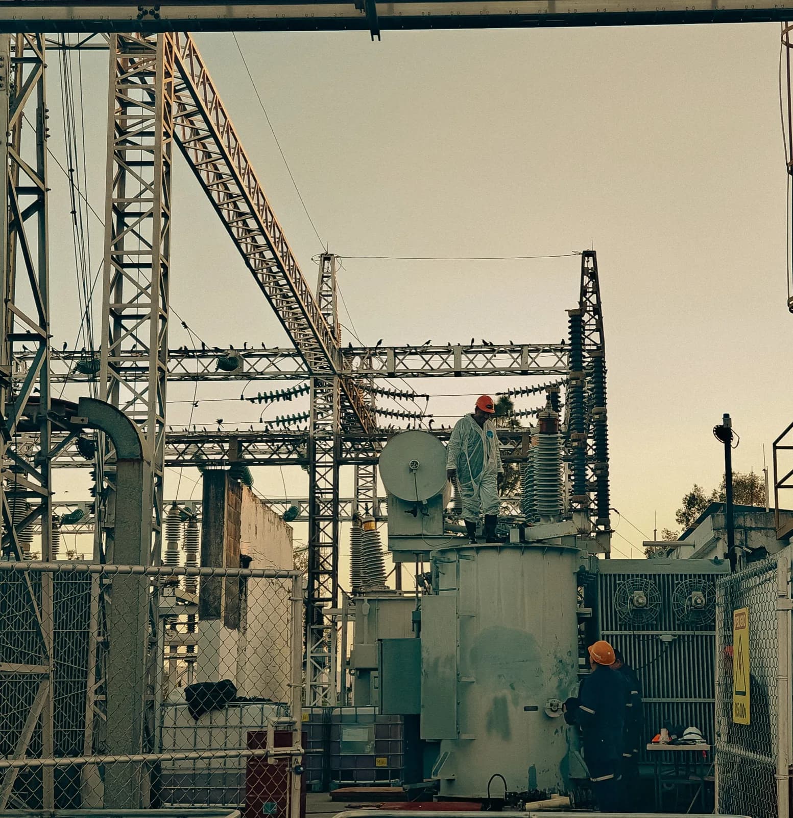 Patio de subestación con un transformador de potencia y su estructura, a contraluz