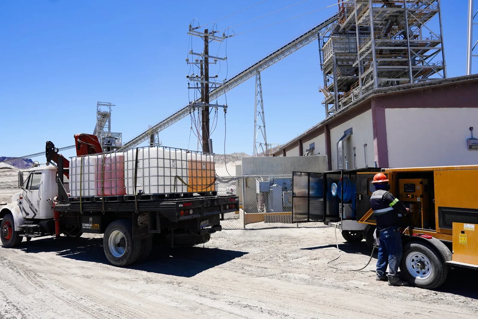 Camión con contenedores IBC y equipo de tratamiento de aceite en el patio de una instalación industrial