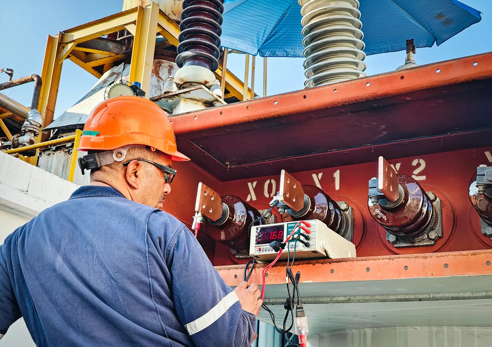 Técnico conectando las puntas de un instrumento digital a las terminales de baja tensión X0, X1 y X2 de un transformador de potencia