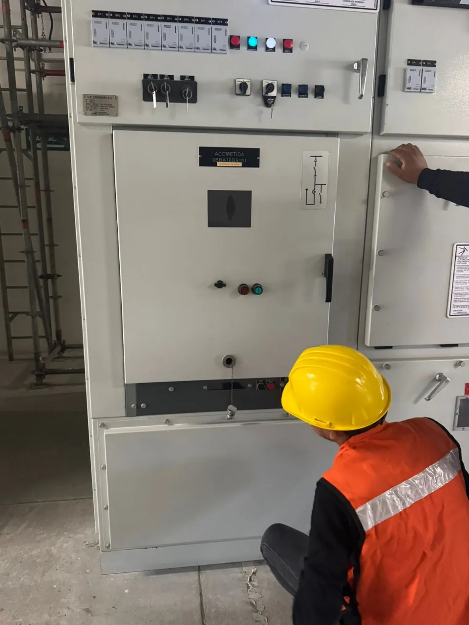 Técnico abriendo la puerta de un tablero de control con instrumentos de medición y botonera en el frente