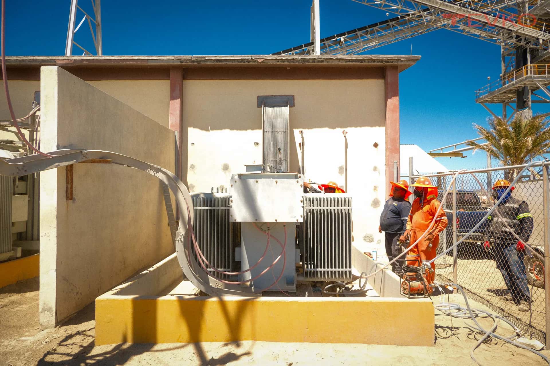 Transformadores de distribución sobre base de concreto en la subestación de una planta industrial, con personal alrededor