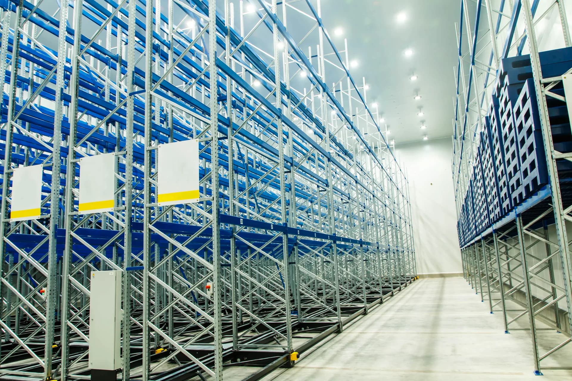 Pasillo entre racks de gran altura en un almacén congelado, con estructura metálica y suelo escarchado.